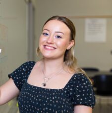 A UNC Charlotte student writes “Let’s be text detectives” on a whiteboard in a classroom.