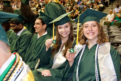 Graduates show their commemorative coins from the Alumni Association.