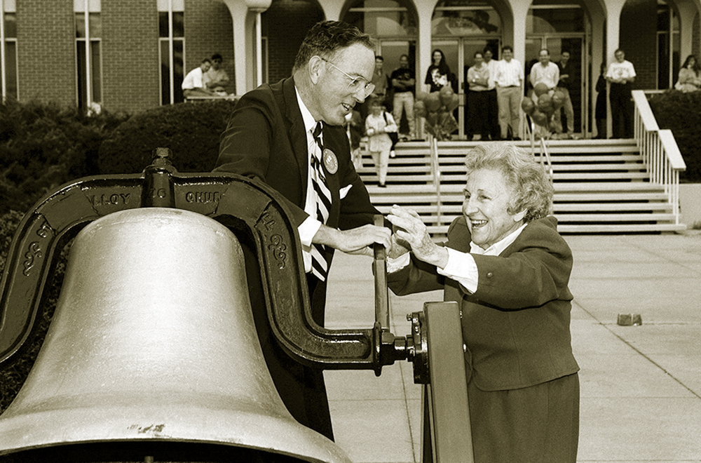 Founder Bonnie E. Cone with Chancellor E.K. Fretwell ringing the victory bell in 1993 celebrating the approval to add Ph.D. programs.