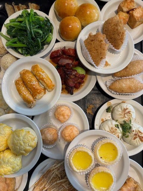 Full plate A variety of dim sum dishes on multiple plates, including dumplings, pastries, buns, and egg tarts.