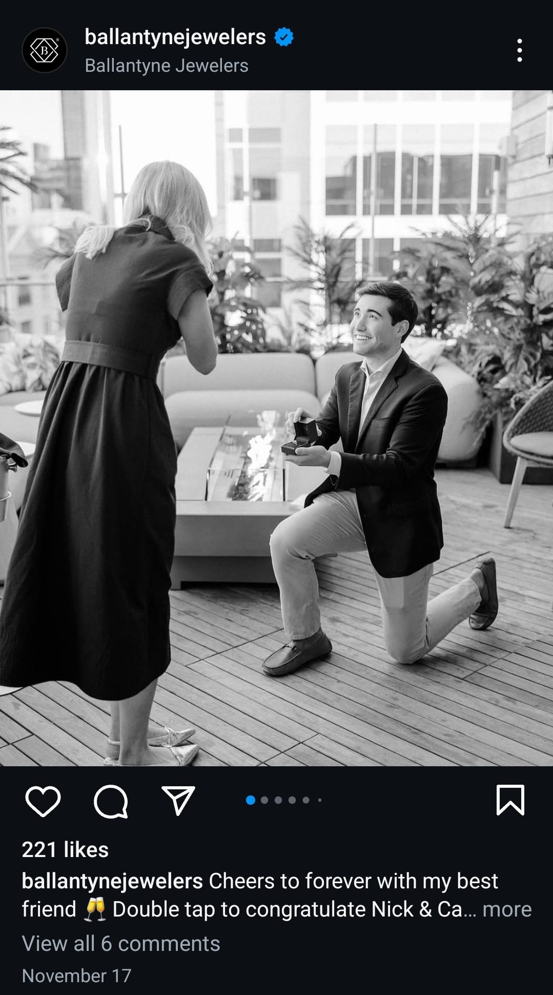 A black and white photo of a couple posing for an engagement photo. The man is down one one knee.