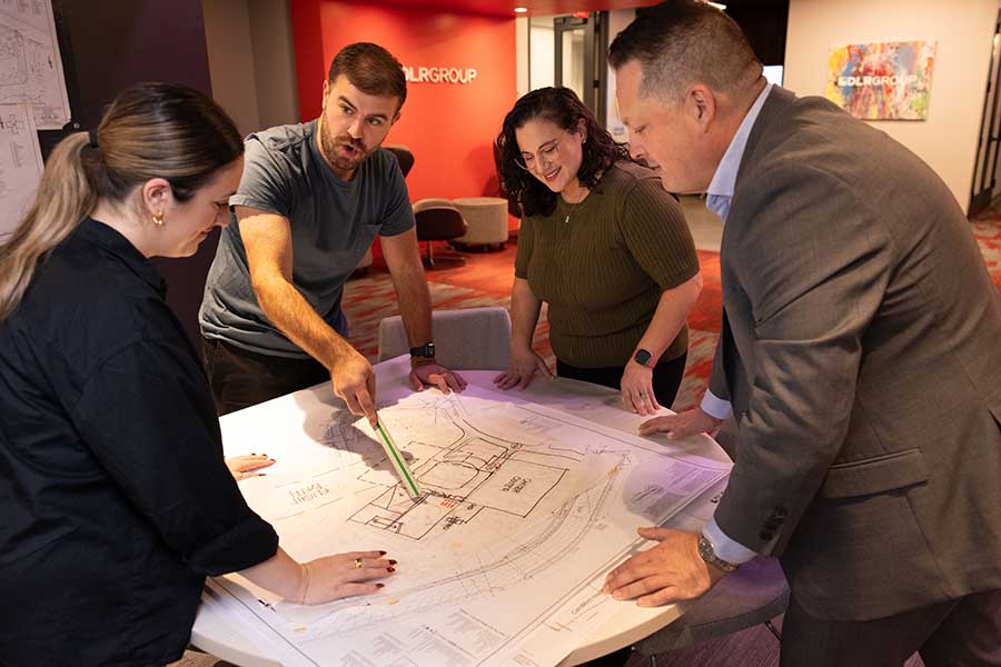 Four architects standing around a table with building plans laid out.