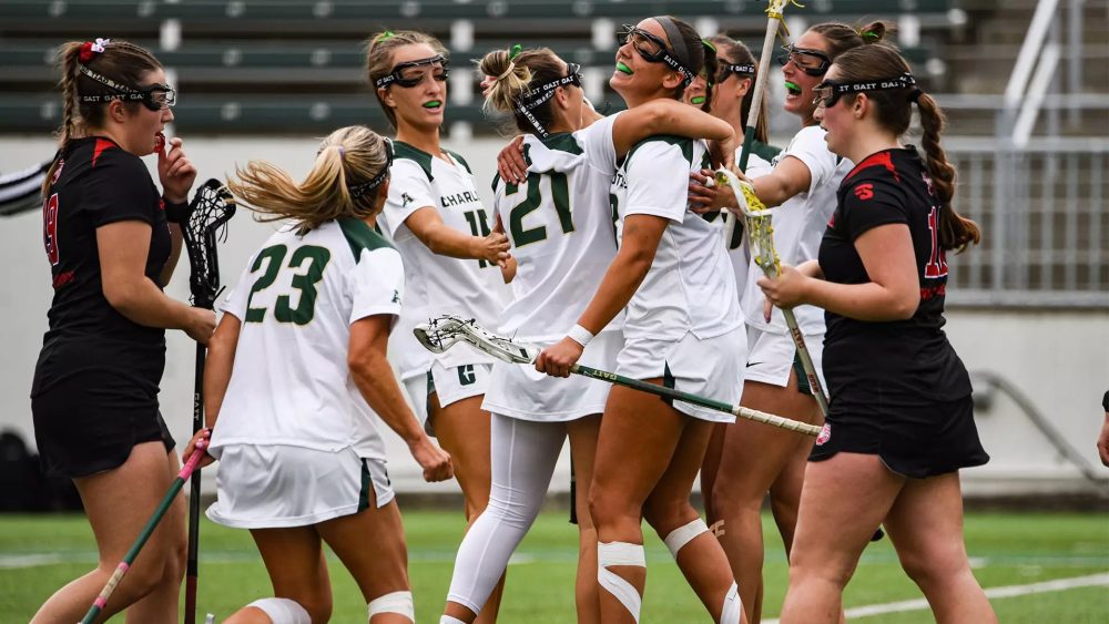 Charlotte 49ers women’s lacrosse players celebrate on the field during a game.