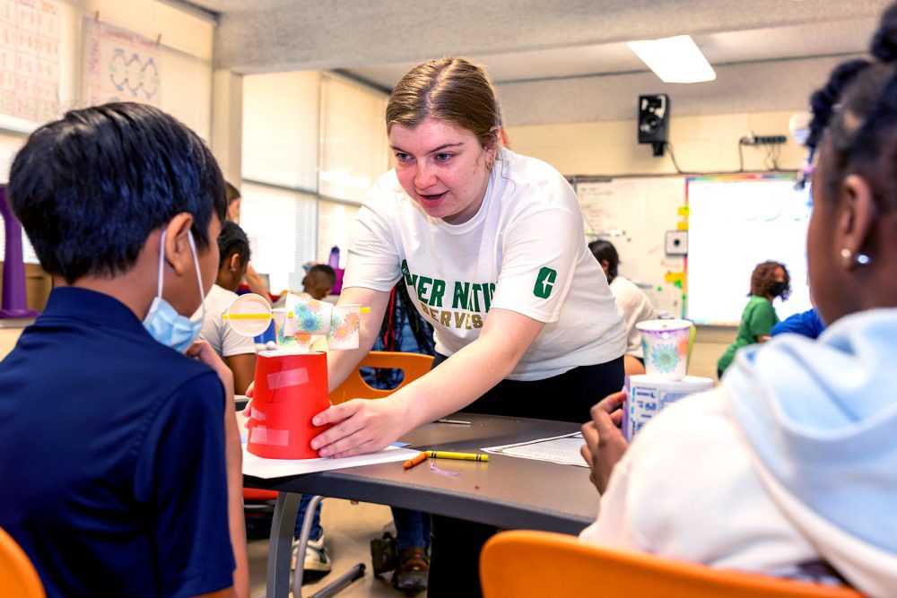 College student helps kids with a hands-on classroom project.