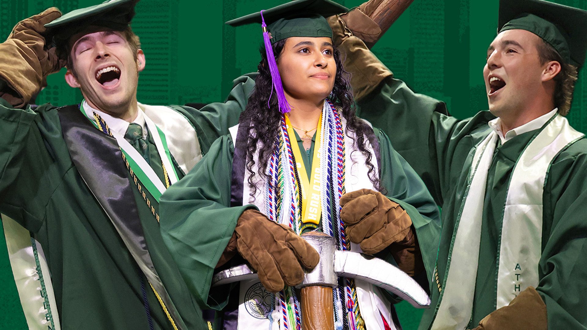 Three UNC Charlotte graduates in green caps and gowns celebrate, with one holding a ceremonial pickaxe and wearing multiple cords and stoles.
