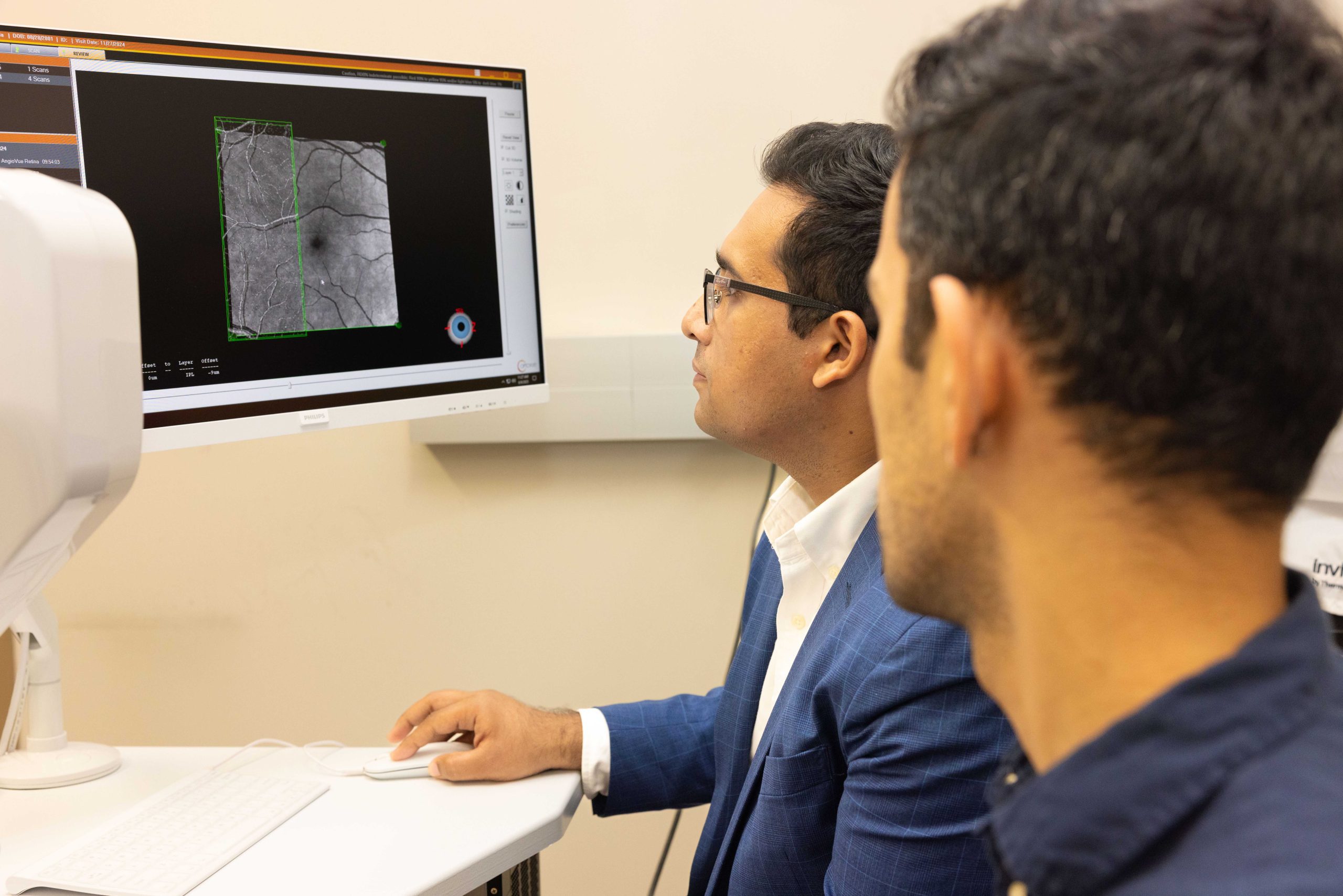 Eyes-vision_Sina+Minhaj_25015_4556_ah Two researchers examine a grayscale eye scan on a computer screen.