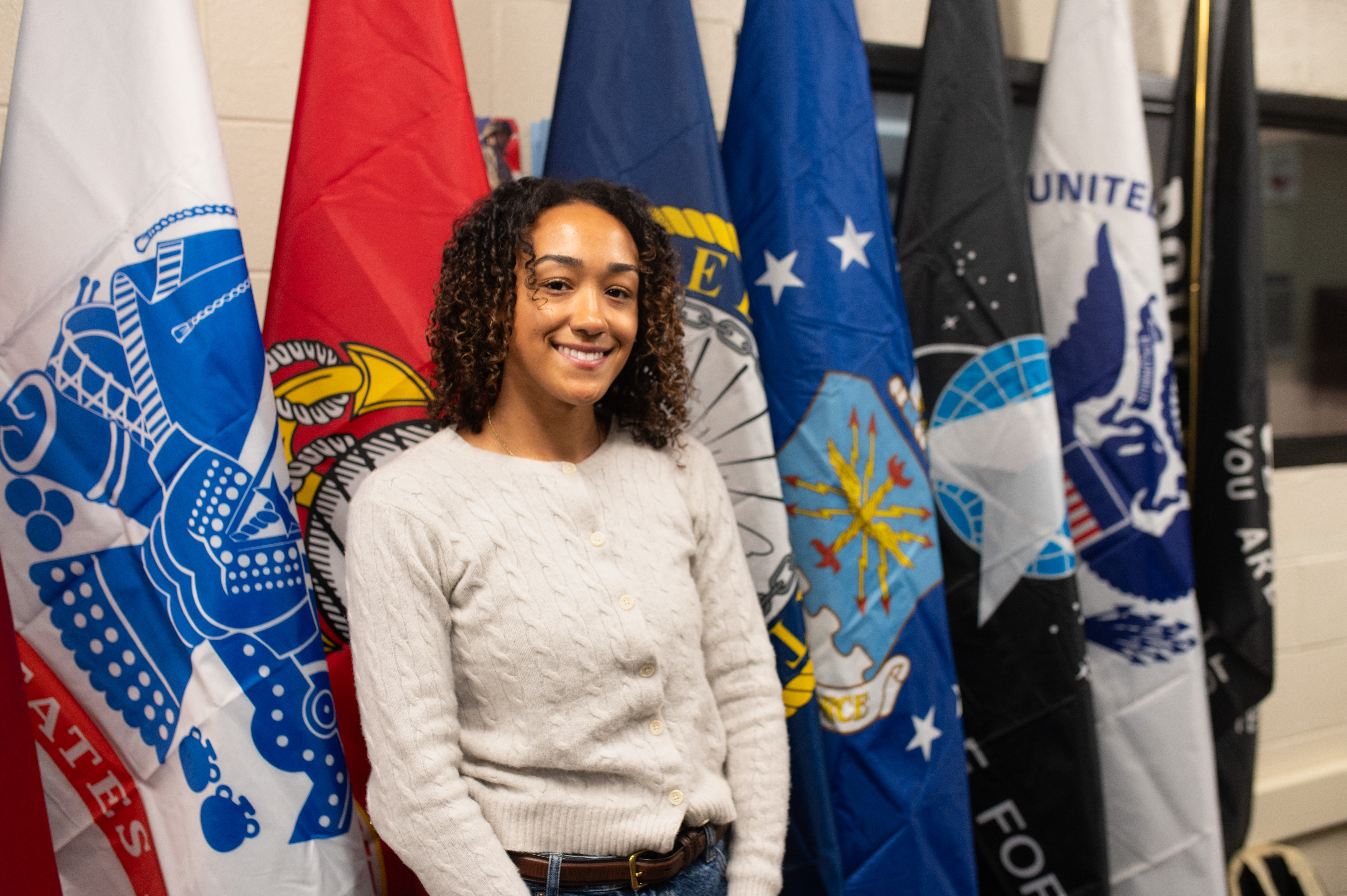 McKenna Samuel stands in front of service flags in MVS Office