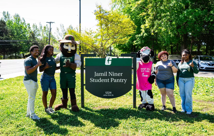 Niner Pantry student workers, Norm the Niner and the Chick-fil-A cow pose for a picture