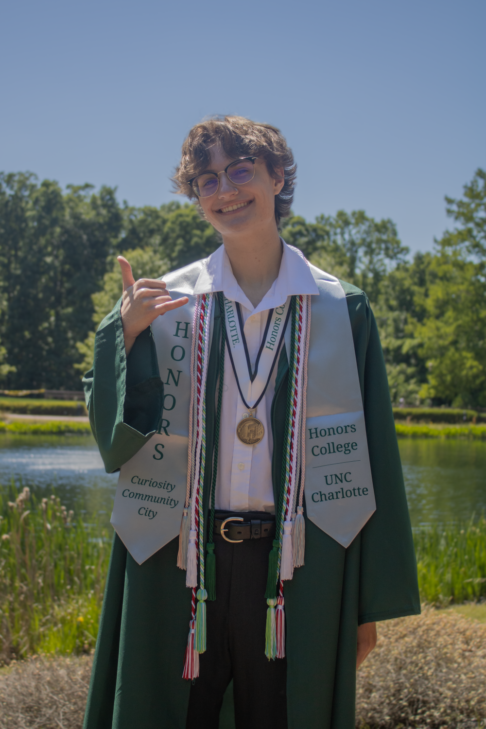 Foster Duckworth poses with gown in stoles in front of Hech Lake