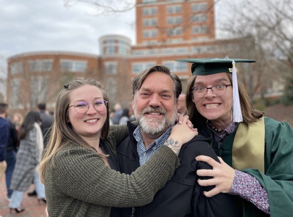 Father Kenny stands in between Madison and Brendan on Brendan's graduation day