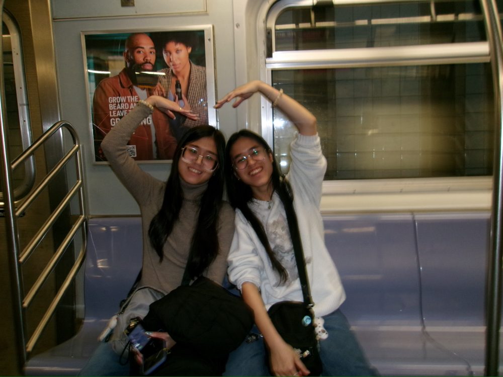 Erica and Monica Phann make heart shape with hands on New York Subway
