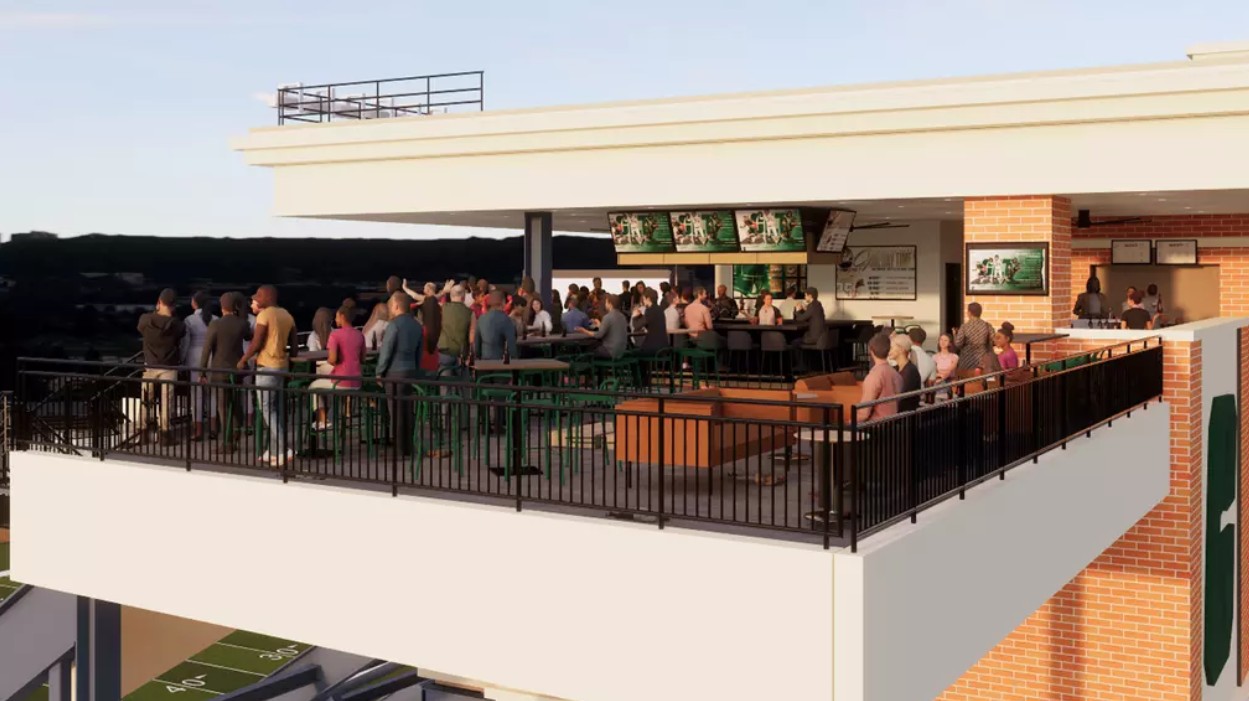 Rendering 4 Rendering of an upper-level outdoor hospitality terrace at Jerry Richardson Stadium, with fans gathered around a bar, standing tables, and lounge seating overlooking the football field.