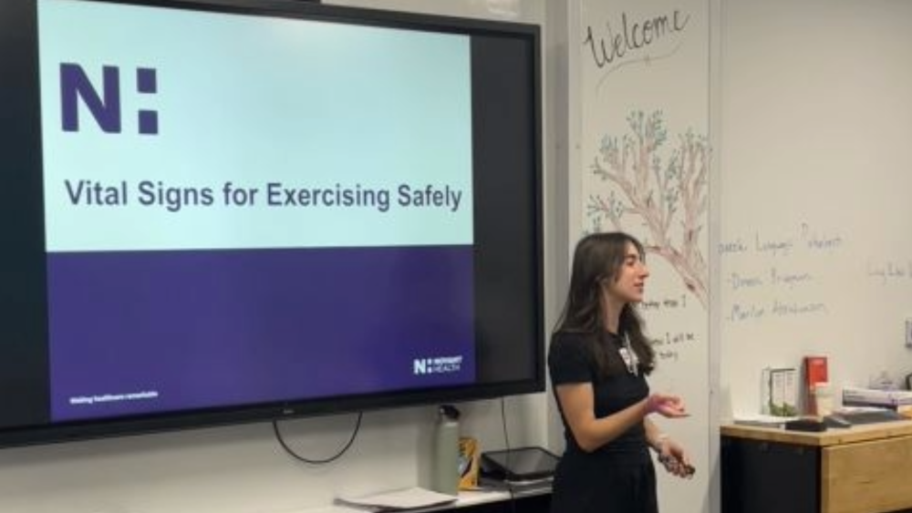 Allison Wade speaks in front of a presentation titled Vital Signs for Exercising Safely