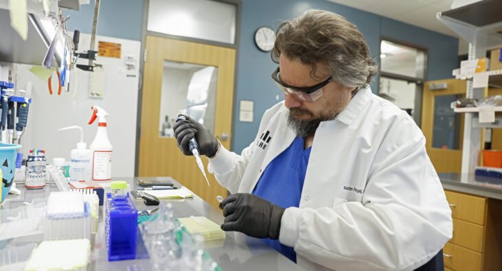 KCOS_Afonin_Lab_24035_6924_kpl A scientist wearing safety goggles works with a pipette in a laboratory setting.