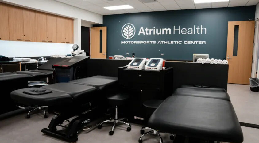 Treatment room at the Atrium Health Motorsports Athletic Center with therapy tables, rehabilitation equipment, and clinical workstations for athlete care.
