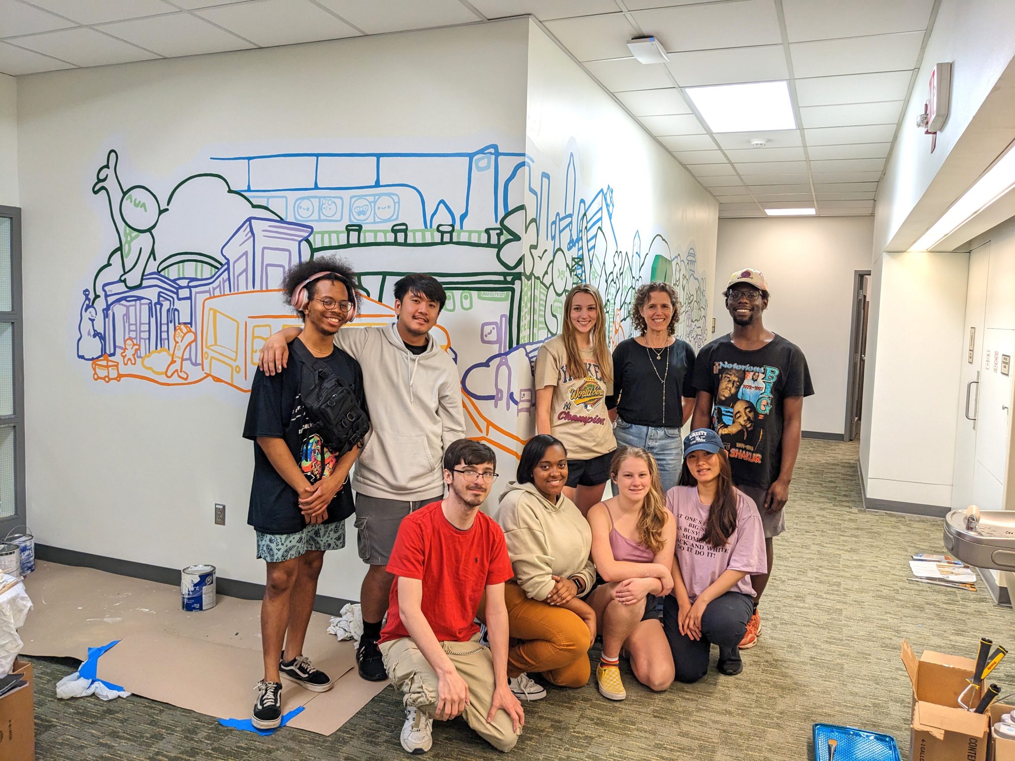 Graphic design students pose with the mural they created for Business Affairs.
