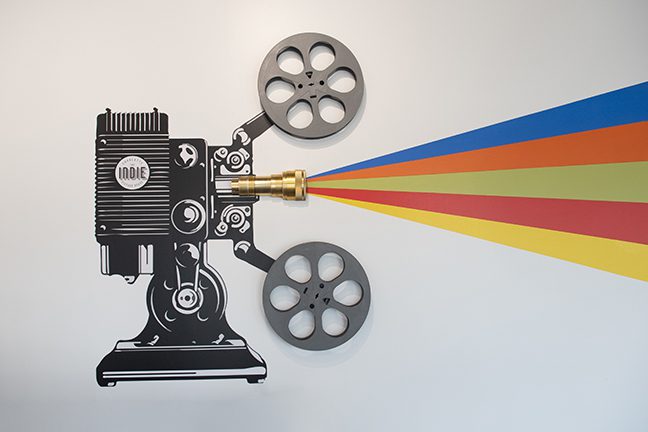 Wall mural that includes a real projection lens embedded in the wall