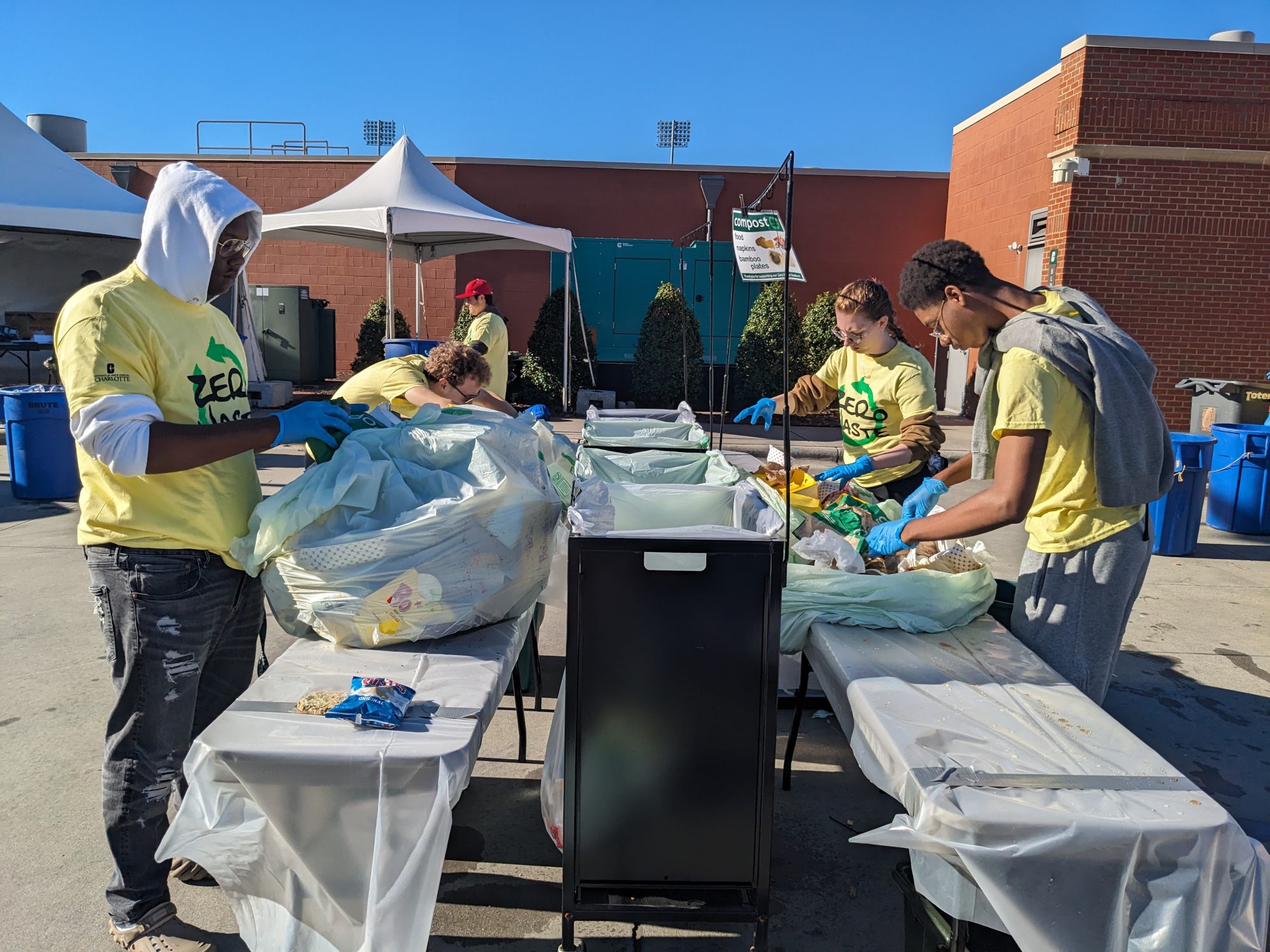 Zero waste volunteers sort through recycling at a football game.