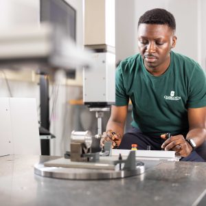 Adeniyi Adeleke, a winner of a scholarship contest sponsored by Zeiss, uses a coordinate measuring machine to measure a part’s feature.