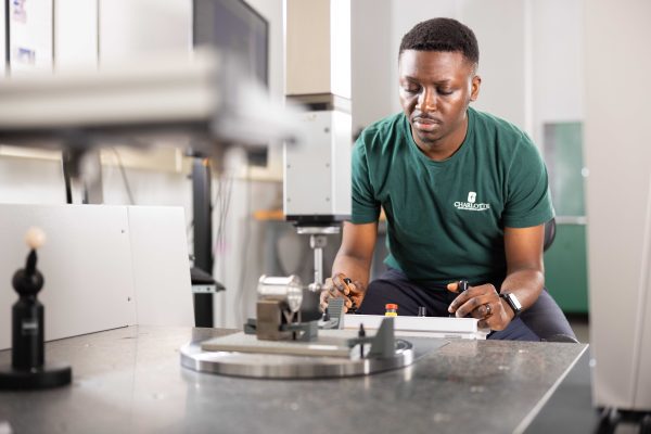 Technician operates precision equipment, focusing on measurements in a lab environment, with instruments visible in the foreground.