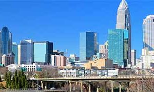 The skyline of Charlotte against a bright blue sky.