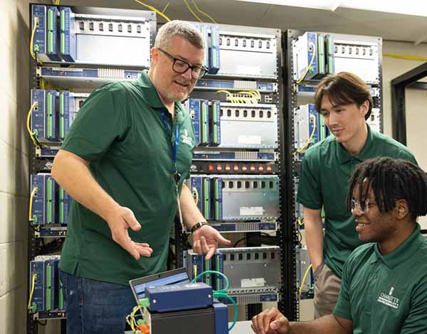 Andy Gould ’13, left, is an engineer with Schweitzer Engineering Laboratories. He is training students to work with state-of-the-art SEL equipment.