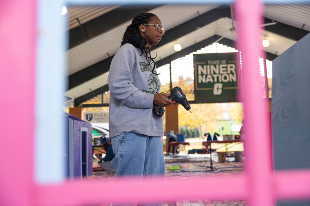 Levine Scholar holds power drill to construct playhouse