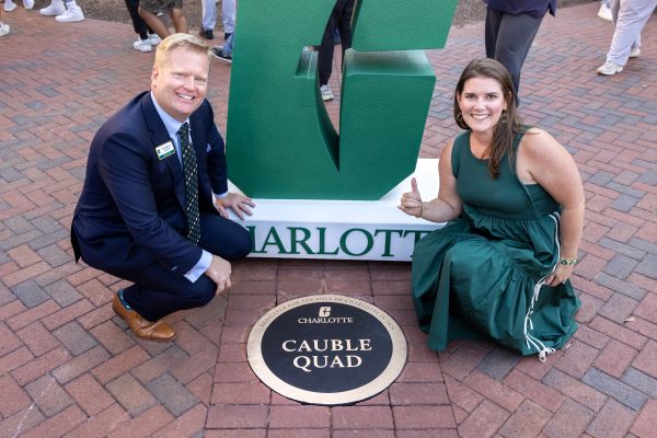 Bo and Angie Cauble have "axes up" as they crouch in front of the plaque marking the new Cauble Quad.
