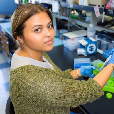 UNC Charlotte student wearing gloves conducts research in a science lab using a pipette and test tubes.