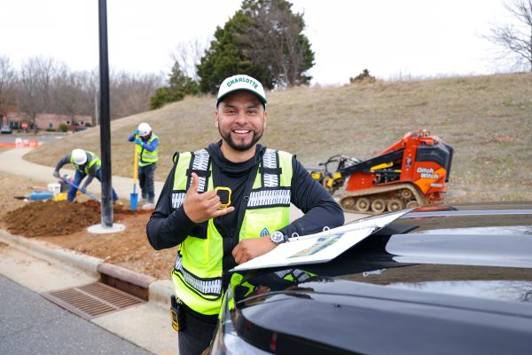Miguel Avila '18 wearing UNC Charlotte hat and holding "picks up" at worksite