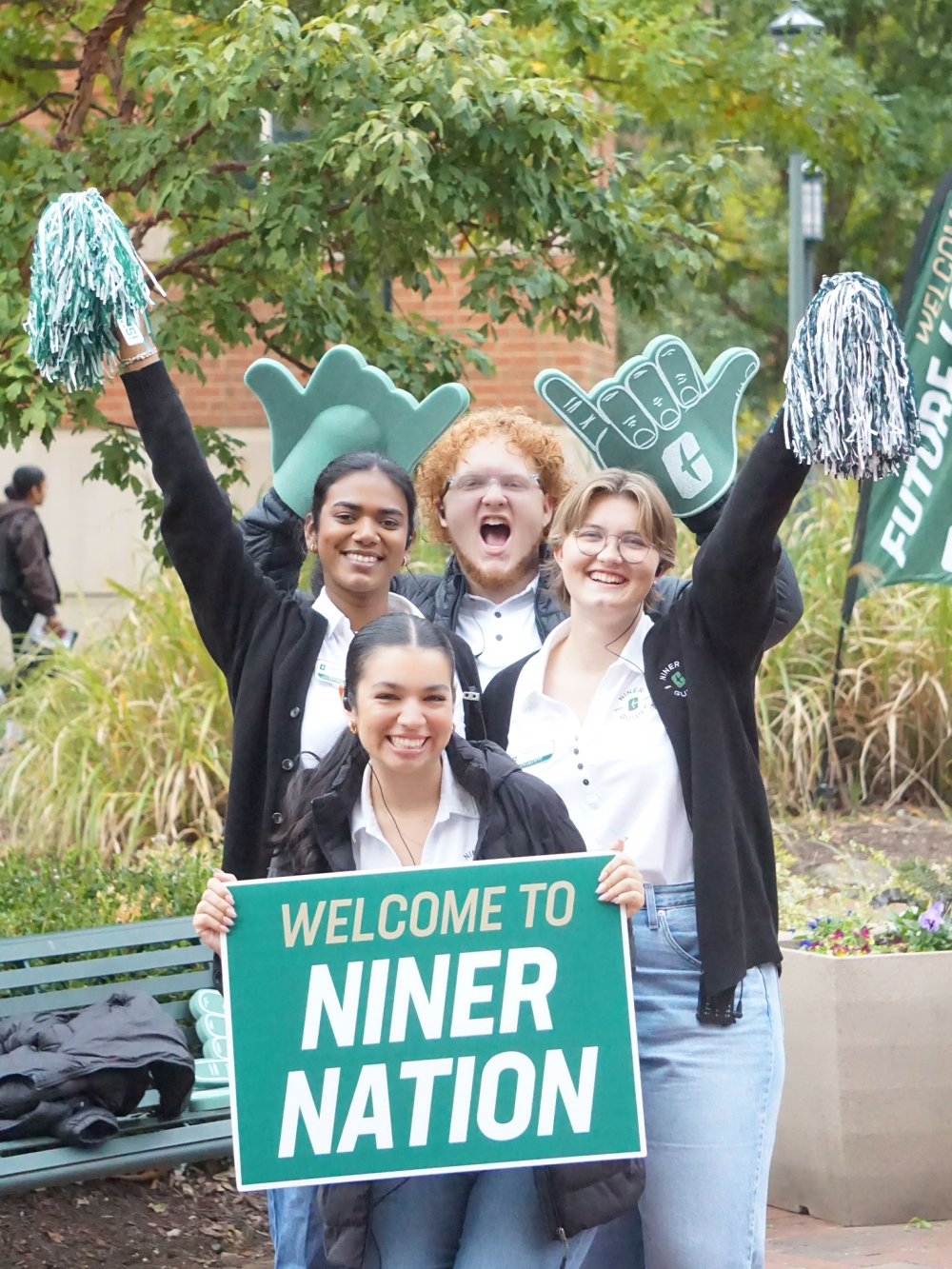 Maryjane Raya and Niner Guides pose it "Welcome to Niner Nation" sign
