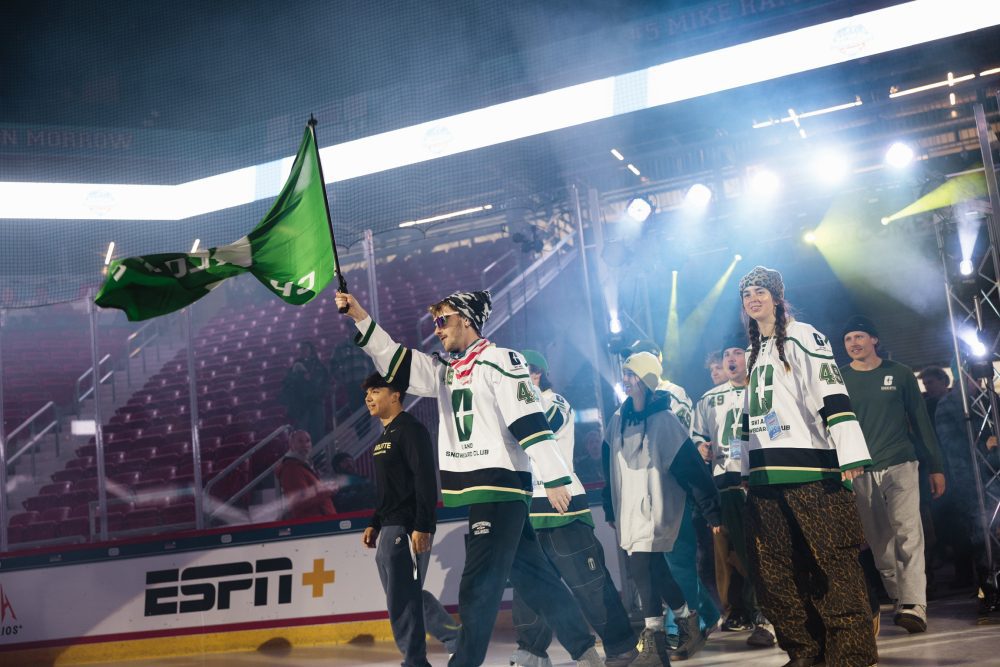 Senior Luke Wilson carries UNC Charlotte flag under arena lighting during the National Championship's opening ceremony