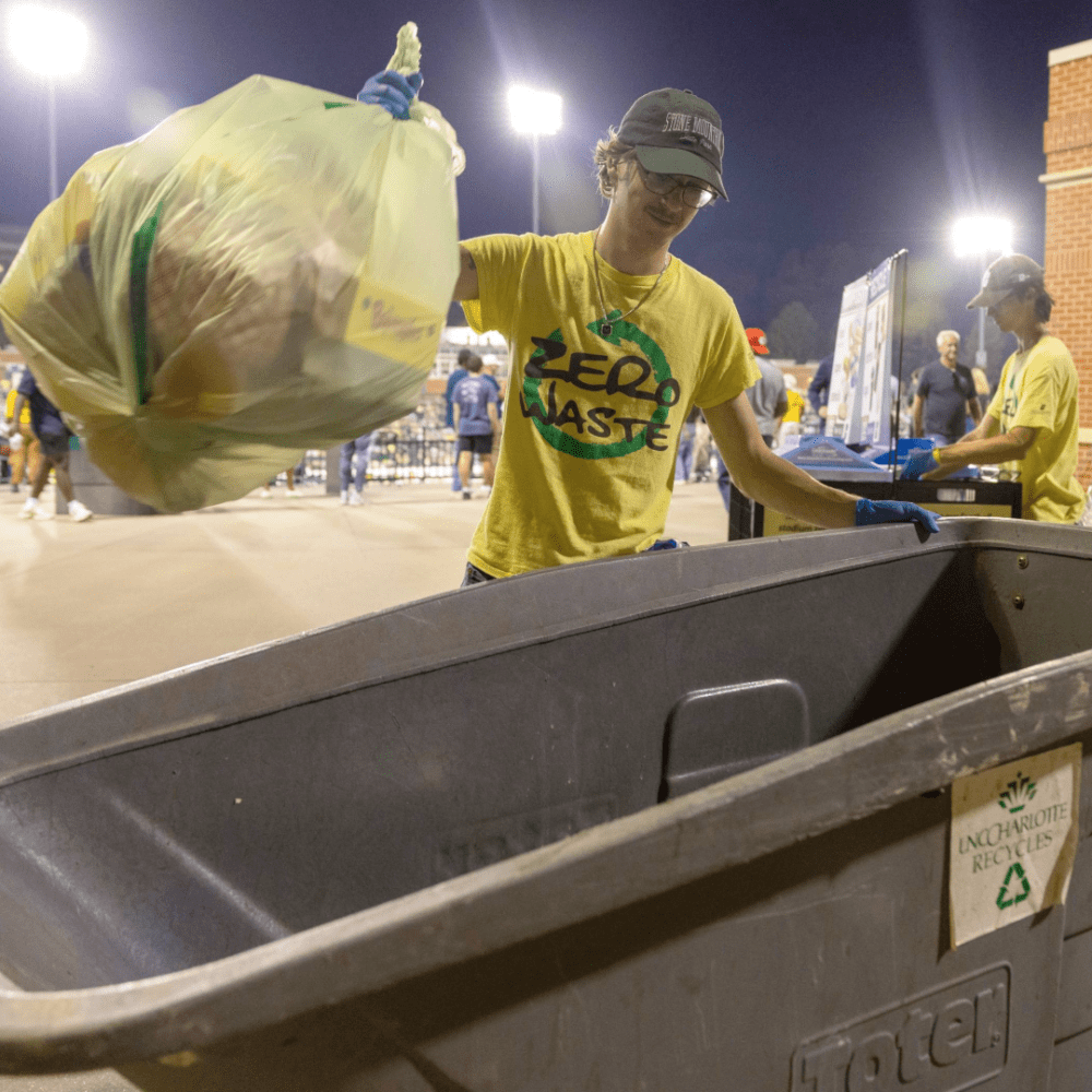 Logan David disposing of trash at Zero Waste football game