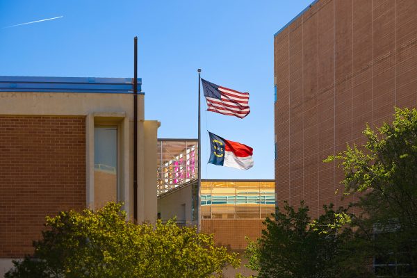 A US flag and NC flag fly on campus.