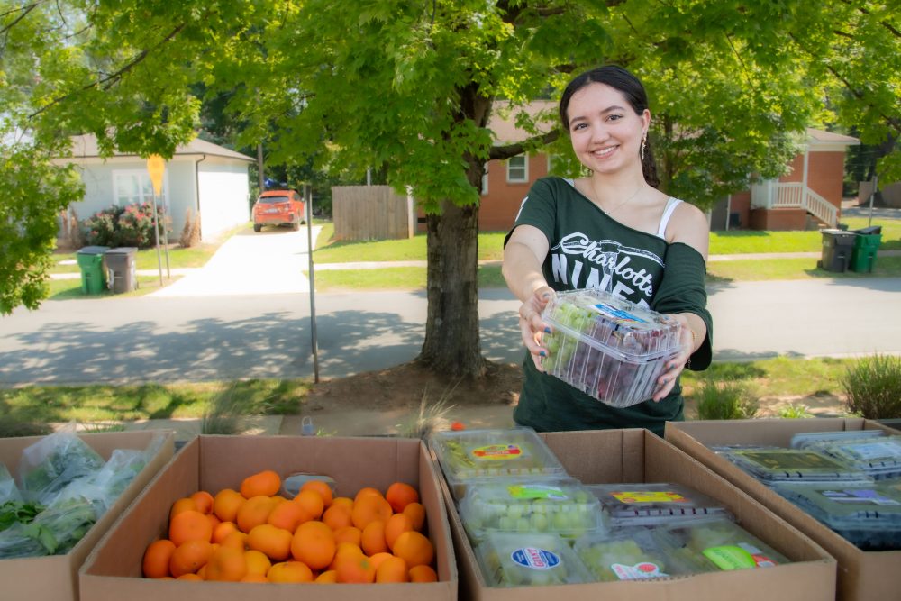 Thalia Dominguez Martinez holds a container of grapes at a mobile market hosted by the Bulb