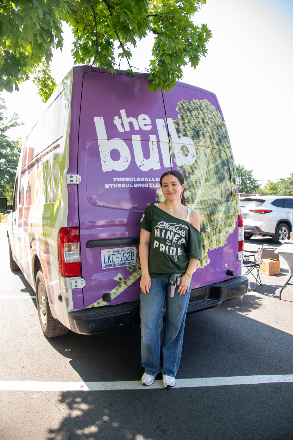 Thalia Dominguez Martinez stands in front of the Bulb mobile unit wearing a Charlotte Niner Pride t-shirt