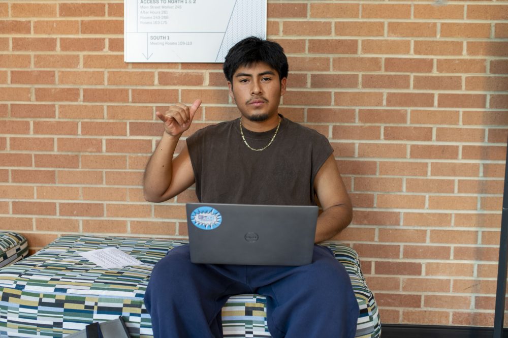 Frist-generation student Angel Vicente holds picks up while setting up his new laptop