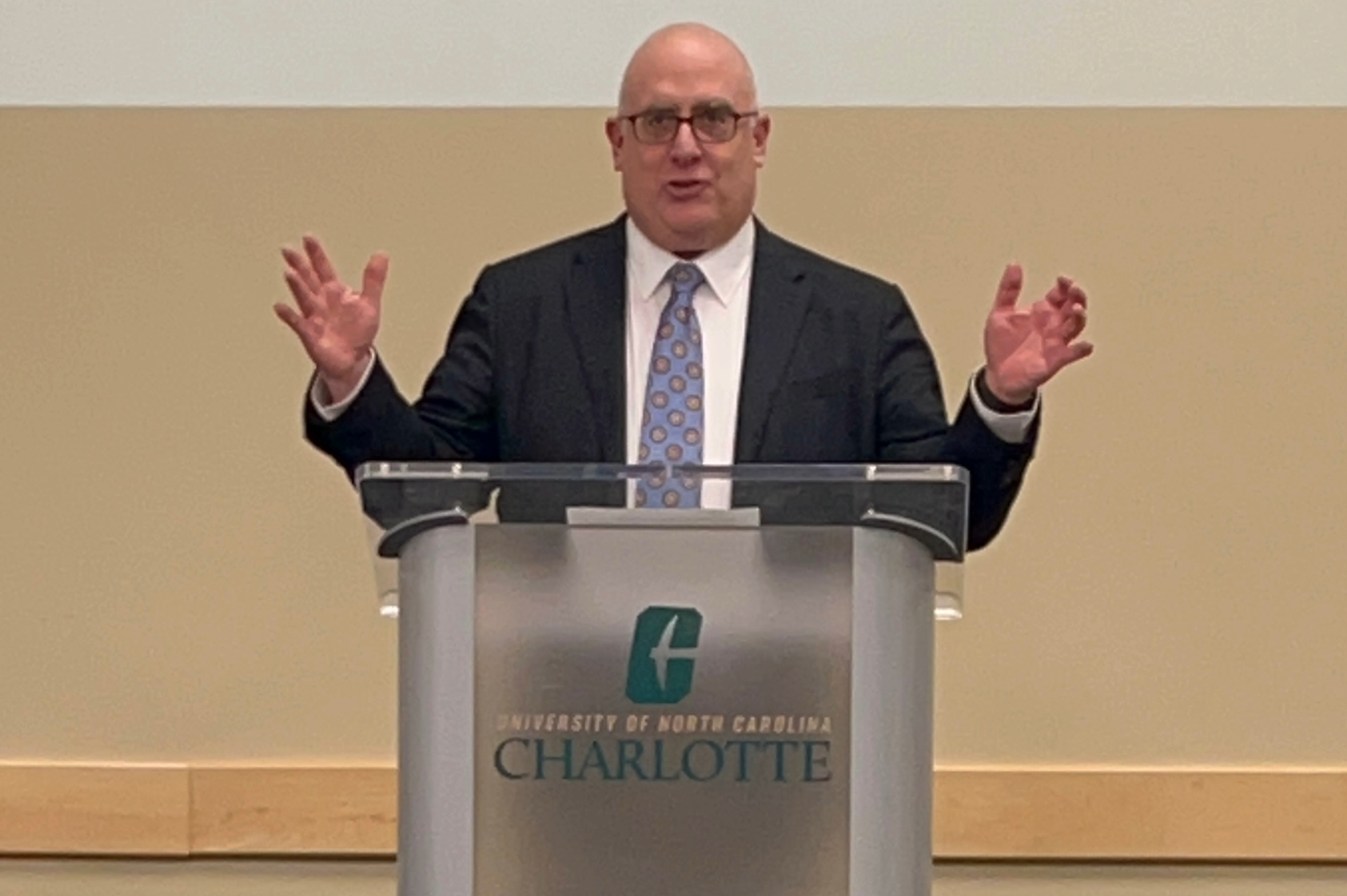 Joe-Posnanski-Speaking Joe Posnanski stands behind a UNC Charlotte podium presenting to a room of Niner Media