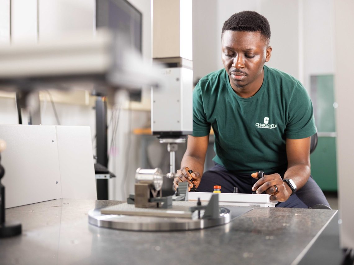 Technician operates precision equipment, focusing on measurements in a lab environment, with instruments visible in the foreground.