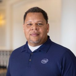 A man in a blue polo shirt stands confidently on a railing