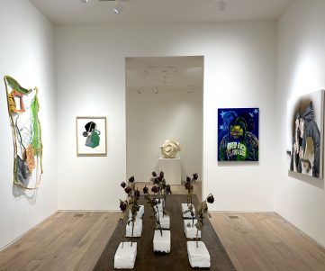 Art gallery with abstract sculptures, paintings, and dried flowers.