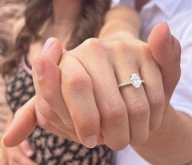 Close-up of hands showing an engagement ring with a large oval diamond.