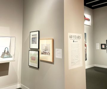 Corner of an art gallery with framed artworks and a text panel titled 