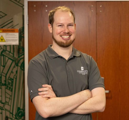 Man standing with arms crossed in front of doors labeled “Charlotte Super Fab Lab.”