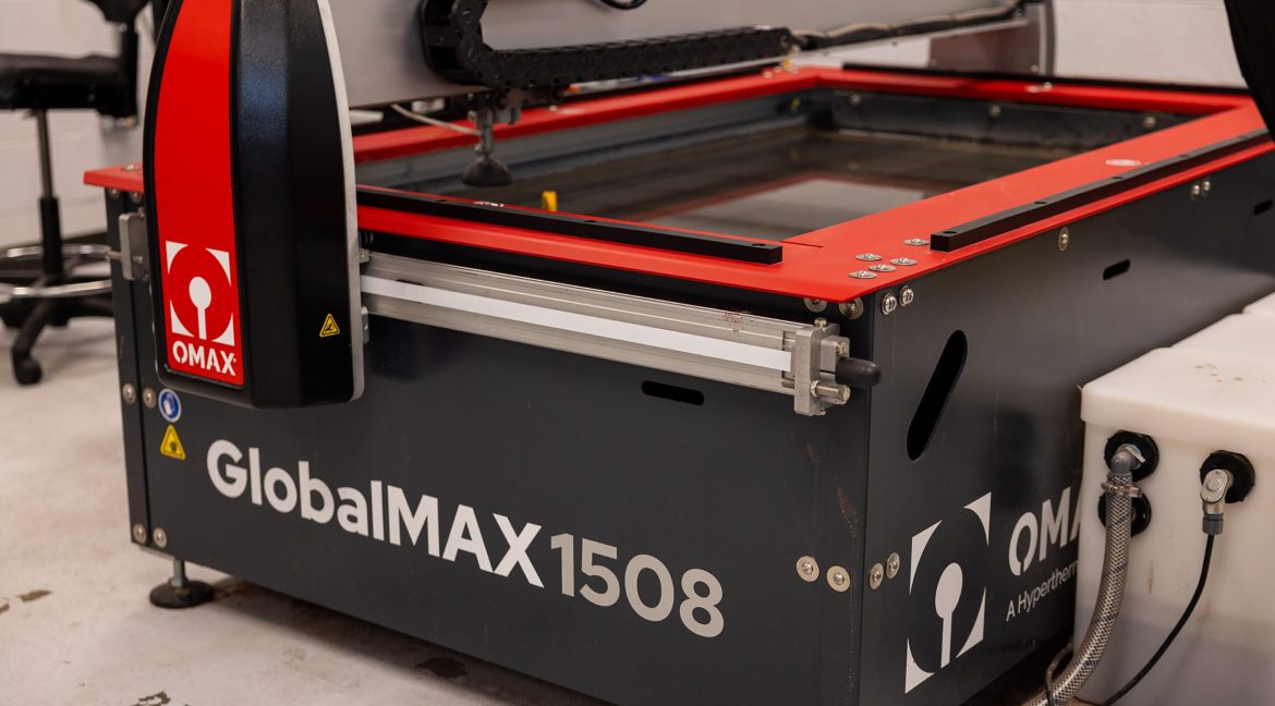 Water jet cutting machine precisely cutting material in a fabrication setting.