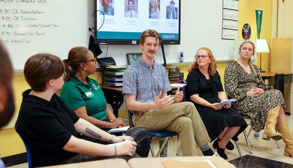 Panel of educators and professionals speaking with students during a classroom session, with presentation displayed on a screen.